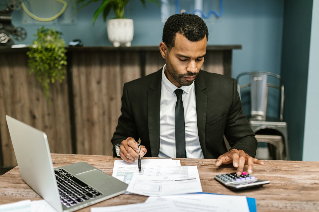A focused businessman works with a calculator and documents in a modern office.